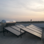 A large grey solar water heater on a terrace facing the sky